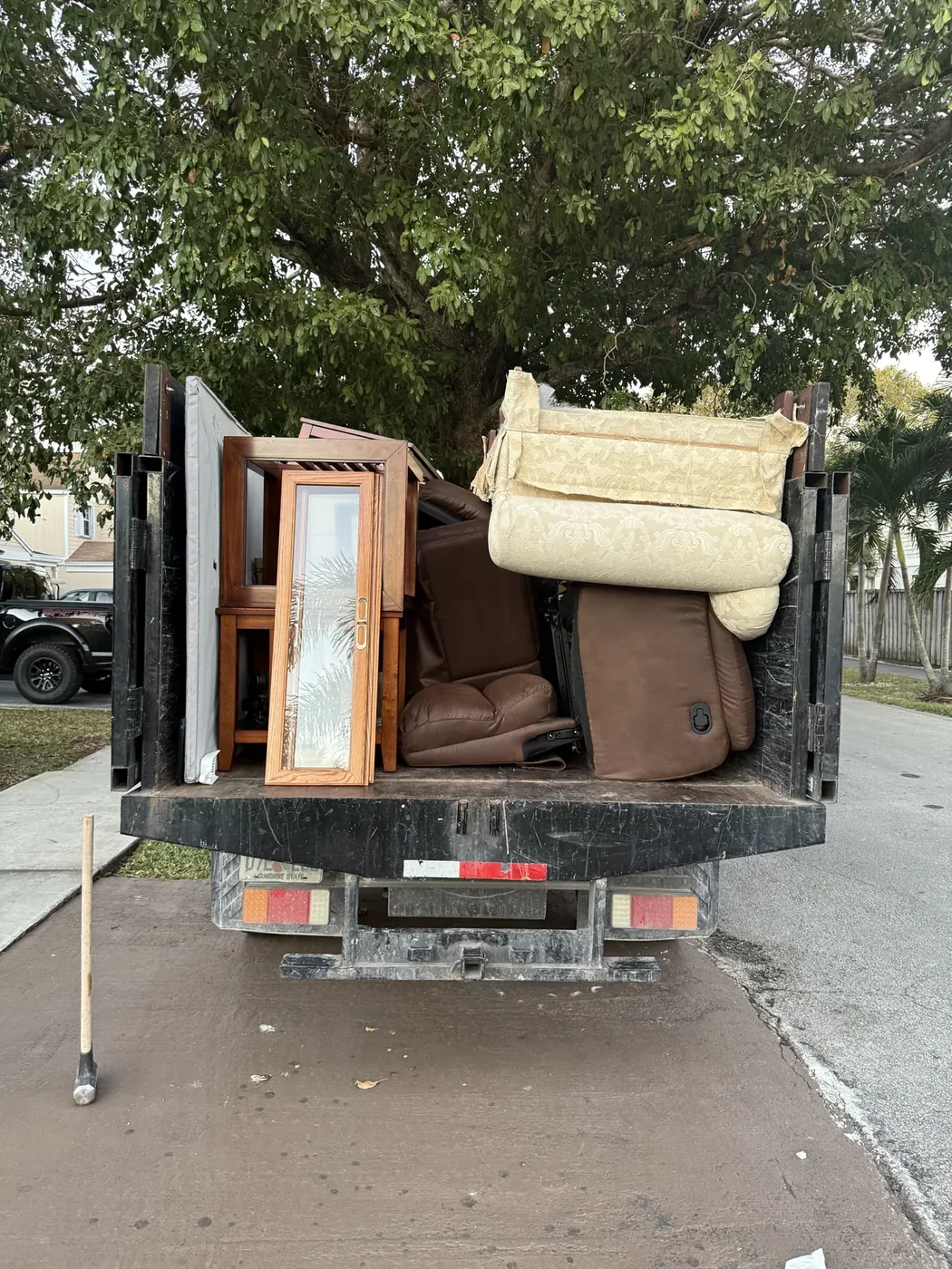 Unwanted sofa and wooden furniture loaded in a 305 Junk Removal truck