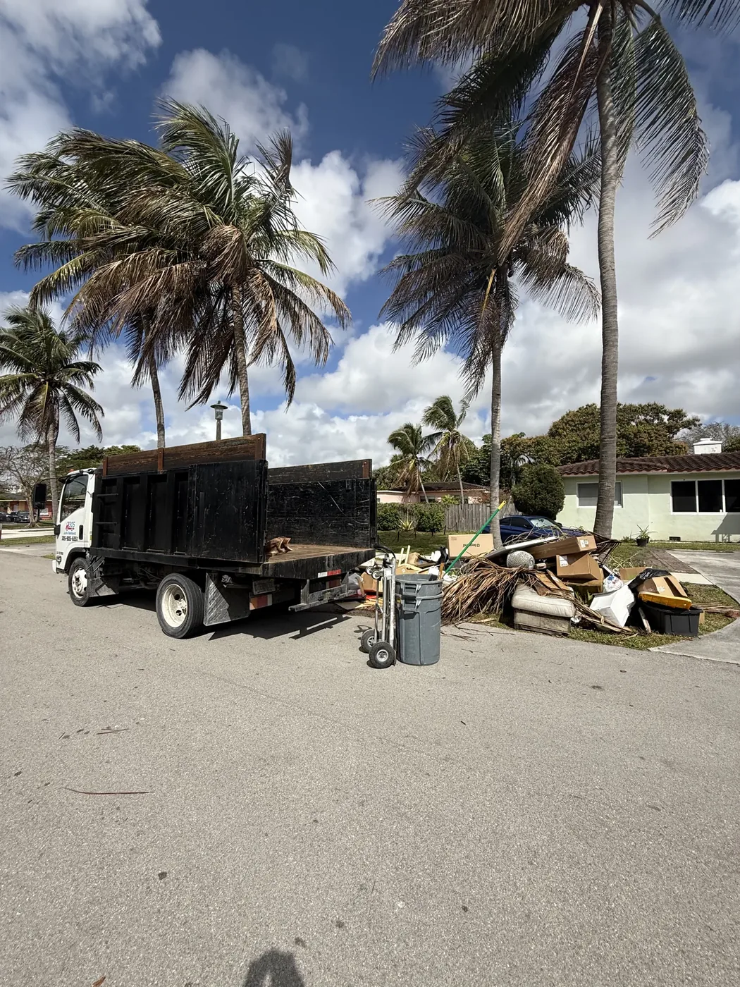 Junk removal truck beside a pile of discarded household materials