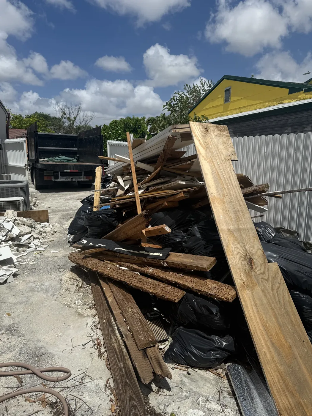 Discarded wood and remodeling debris beside a hauling truck